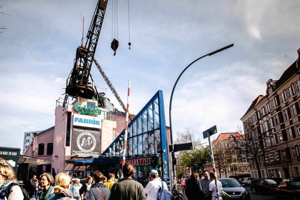 Aussenansicht der Fabrik mit Menschen im Vordergrund.